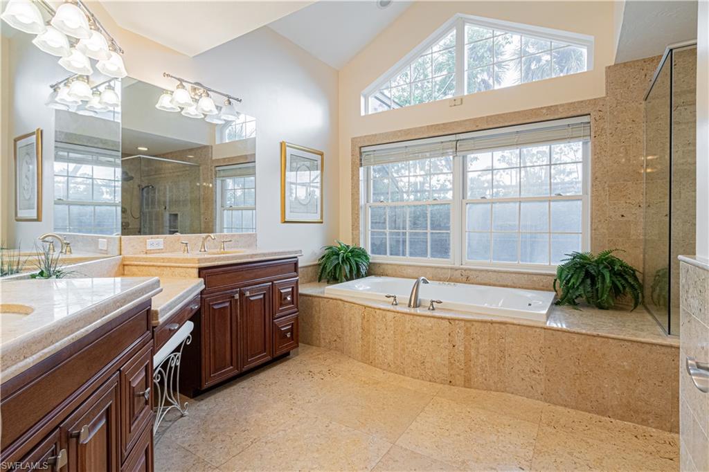 519 Cormorant Cove Naples, FL 34113 - Photo 12 of 32 a spacious bathroom with a granite countertop tub sink and mirror
