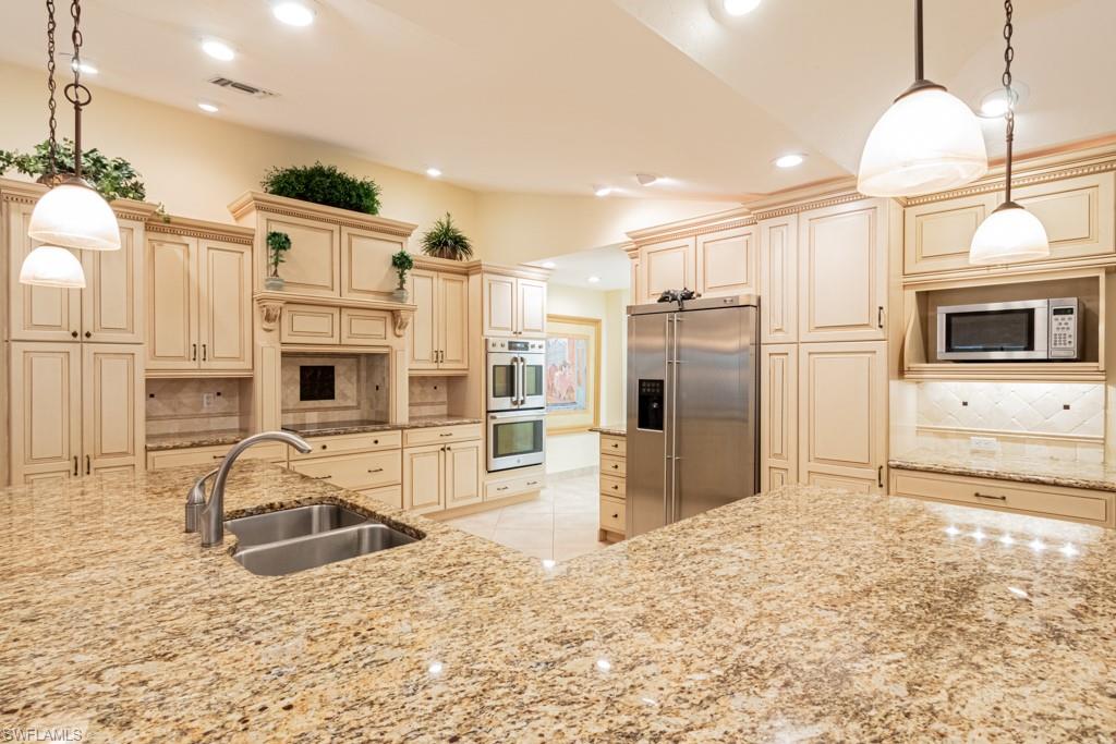 519 Cormorant Cove Naples, FL 34113 - Photo 7 of 32 a kitchen with stainless steel appliances kitchen island granite countertop a stove and a refrigerator