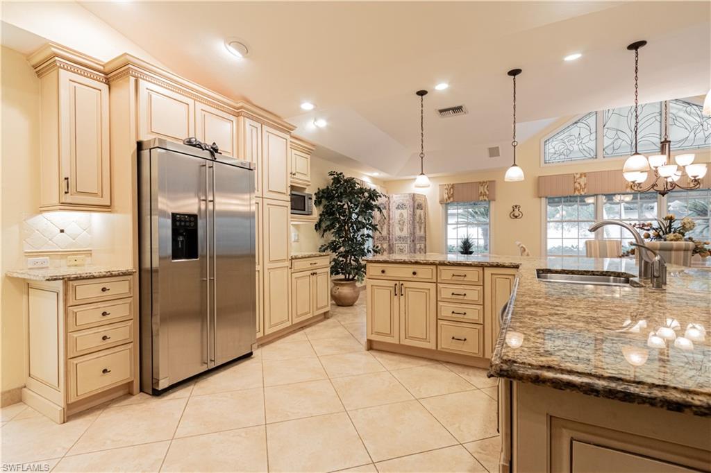 519 Cormorant Cove Naples, FL 34113 - Photo 8 of 32 a kitchen with white cabinets and stainless steel appliances