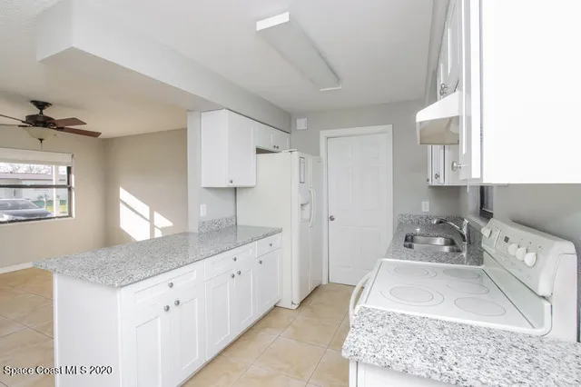 a kitchen with granite countertop a sink a stove and cabinets