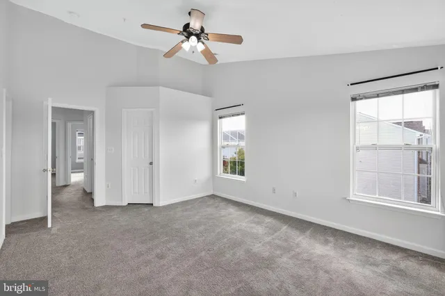 a view of empty room with windows and ceiling fan