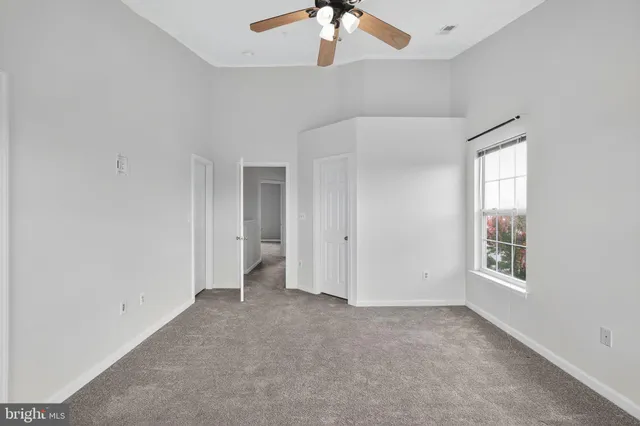 an empty room with windows and chandelier fan