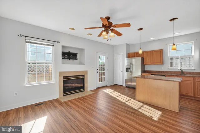 a living room with stainless steel appliances granite countertop furniture wooden floor and a fireplace