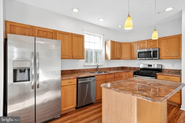 a kitchen with stainless steel appliances granite countertop a refrigerator a sink a stove a microwave and island