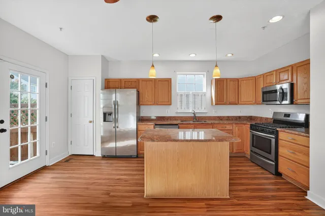 a kitchen with stainless steel appliances granite countertop a refrigerator a stove a sink and a wooden floors