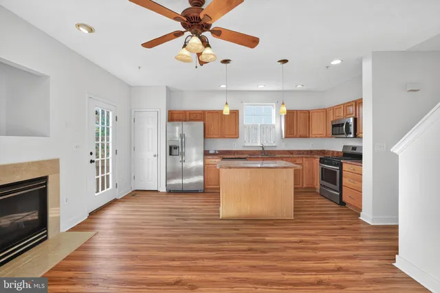 a large kitchen with stainless steel appliances granite countertop a stove top oven a sink and a refrigerator