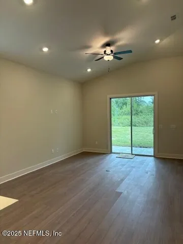 an empty room with wooden floor chandelier fan and windows