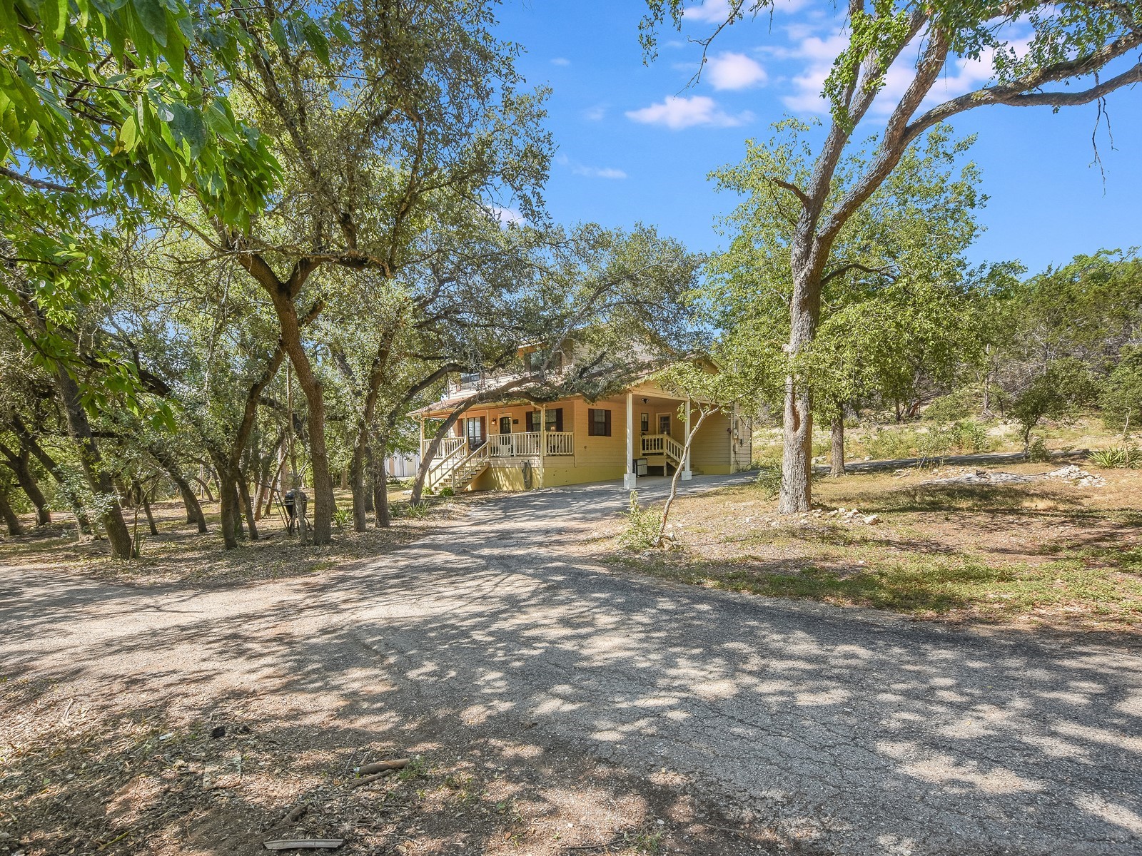 13404 Cedar Lime Road Leander, TX 78641 - Photo 7 of 28 A private, tree-lined driveway leads to a charming residence nestled among mature greenery.