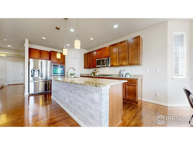 a kitchen with stainless steel appliances granite countertop a refrigerator a stove and a sink with wooden floor