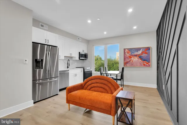 a living room with furniture a refrigerator and kitchen view