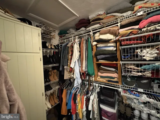 a view of walk in closet with clothes and shoes