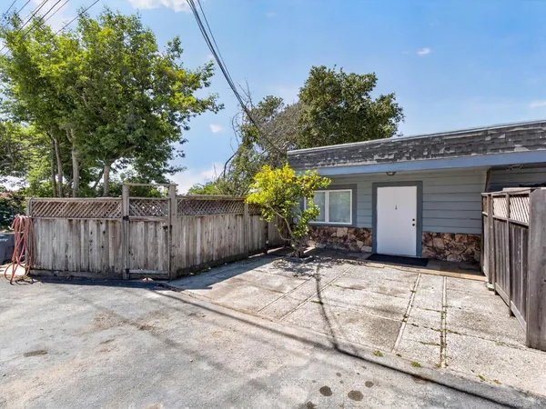 a view of a house with wooden fence and a large tree