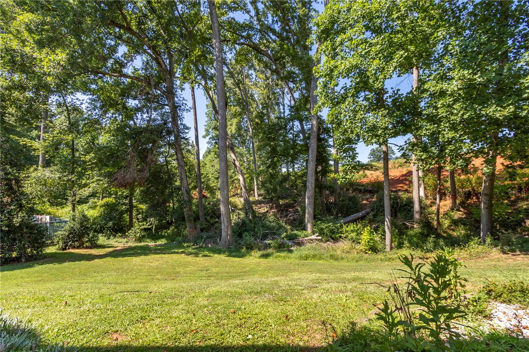 1302 Leeward Road Anderson, SC 29625 - Photo 40 of 50 A verdant lawn gracefully transitions to a backdrop of towering trees and natural woodland.