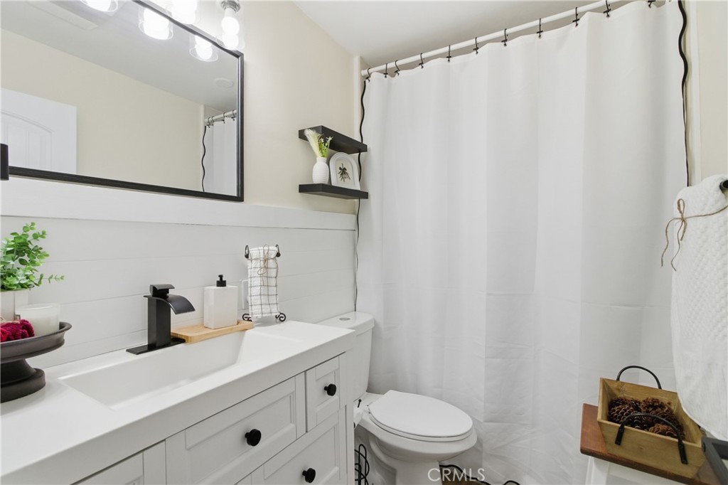 3552 Condalia Avenue Yucca Valley, CA 92284 - Photo 13 of 30 a bathroom with a sink a toilet and shower curtain