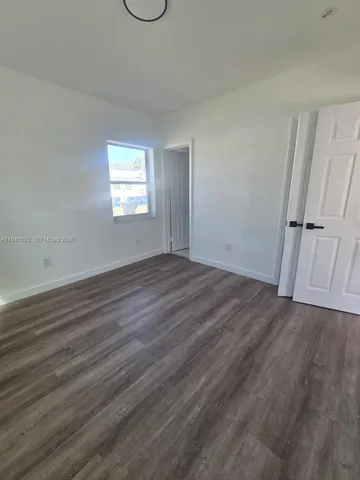 an empty room with wooden floor and window