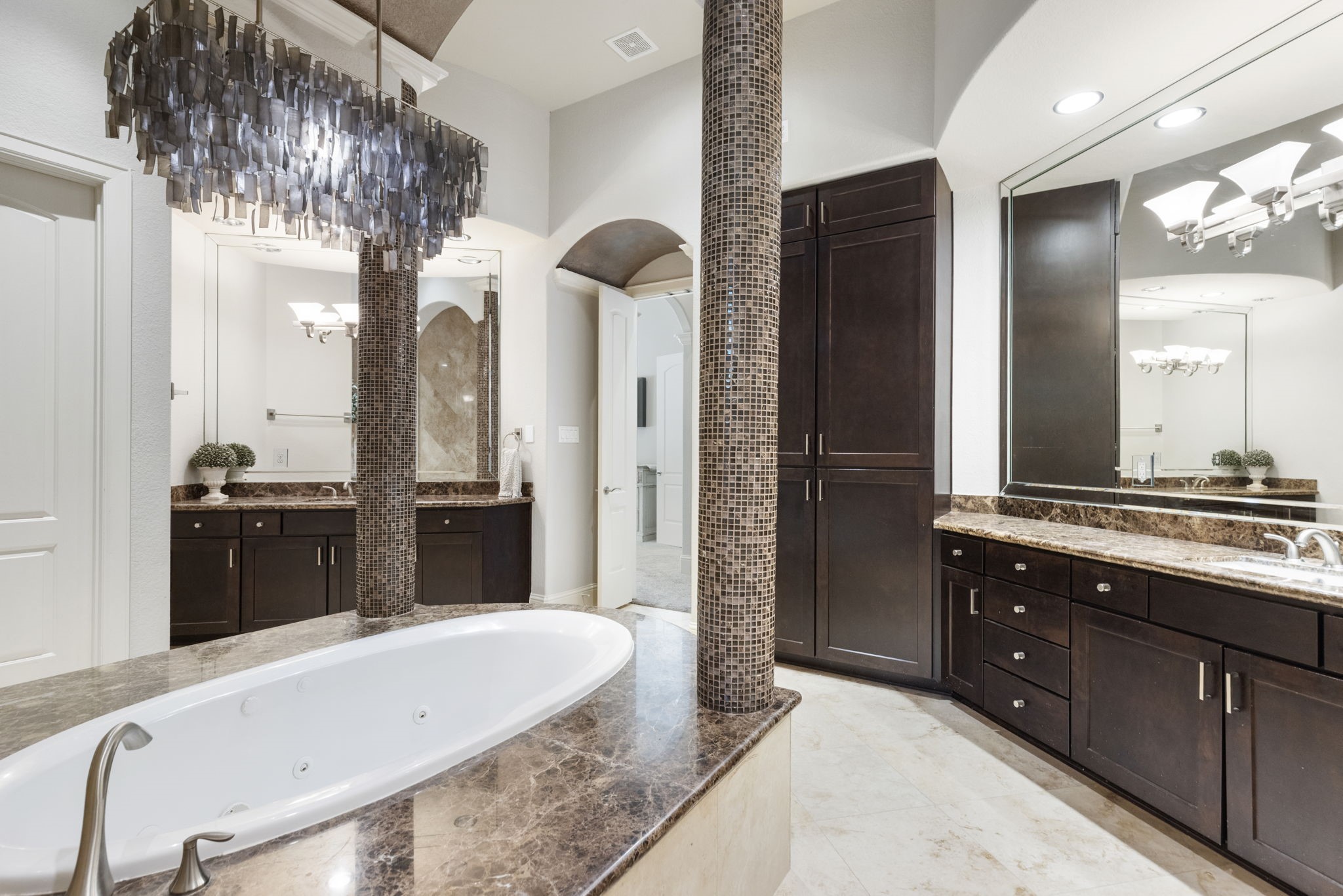 4103 Tee Tree Court Spring, TX 77386 - Photo 14 of 37 Spacious Primary Bath with travertine flooring, dual vanities with granite counters, jetted tub with barrel ceiling accent, and oversized walk-in shower with dual shower heads and bench. Custom cabinetry, built-in linen storage, and TONS of closet space with built-in storage features.