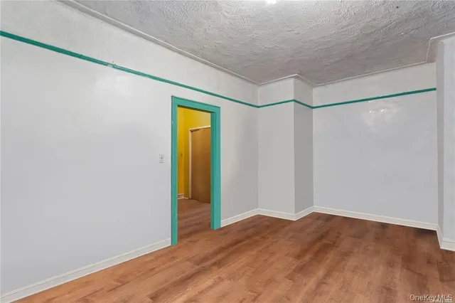 a view of empty room with wooden floor and bathroom