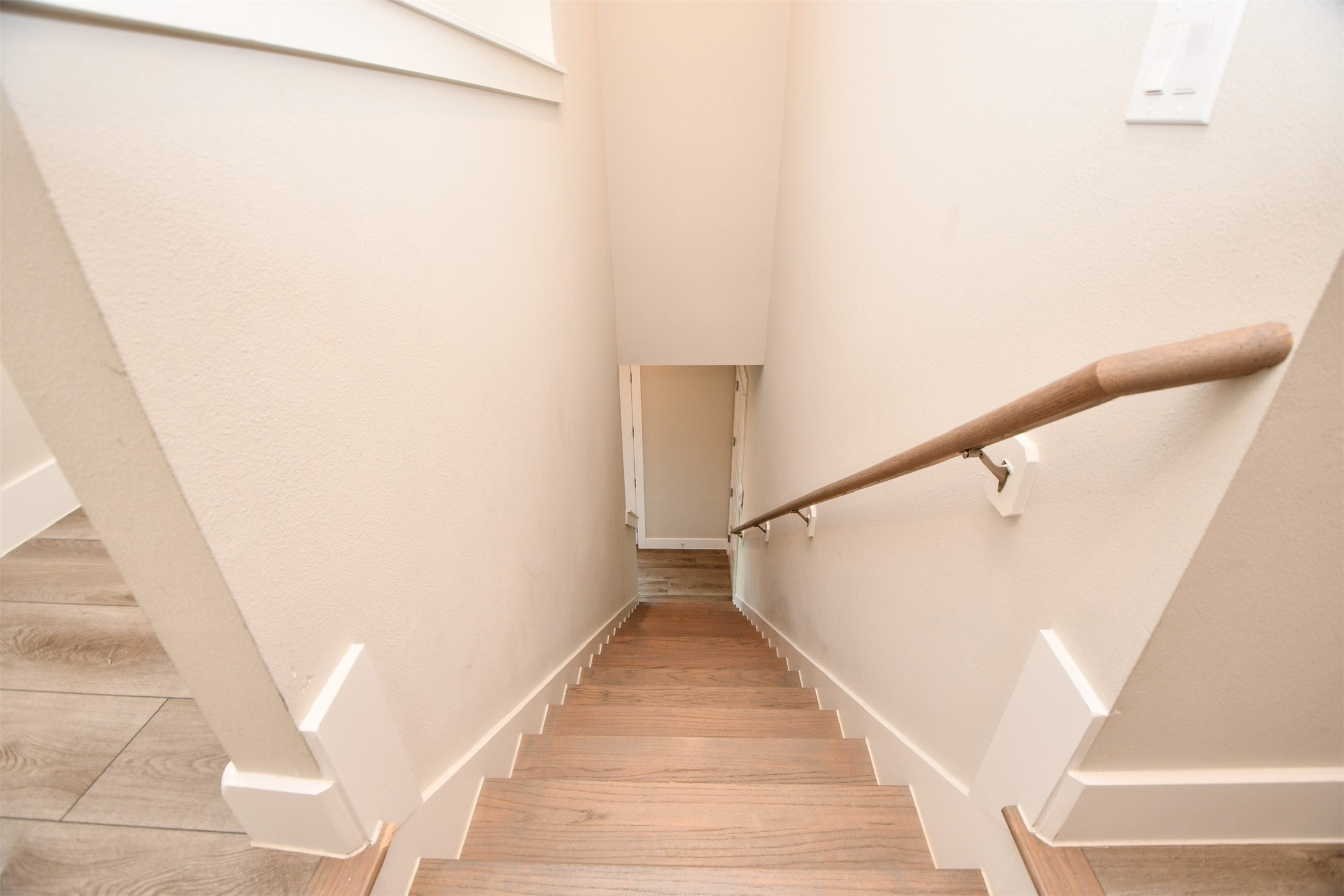 1239 West Tidwell Road Houston, TX 77091 - Photo 16 of 35 This photo shows a narrow staircase with wooden steps and a simple handrail, leading downward. The walls are painted a light, neutral color, creating a clean and modern look.