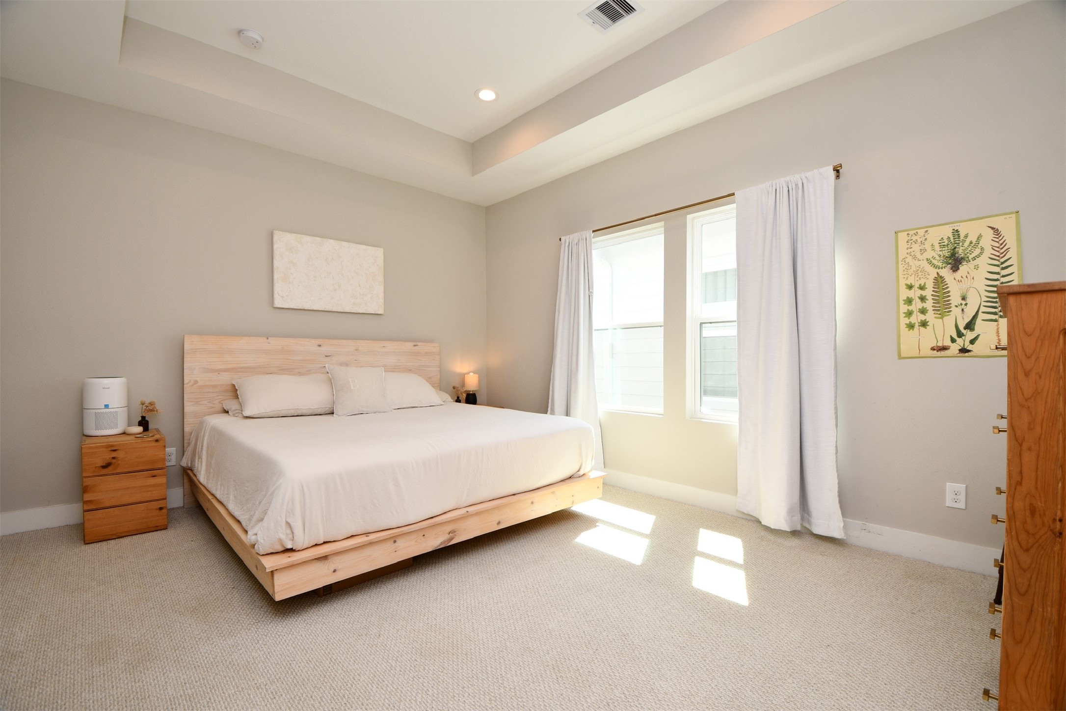 1239 West Tidwell Road Houston, TX 77091 - Photo 17 of 35 This bedroom features a cozy atmosphere with neutral tones, a large bed with wood accents, ample natural light from two windows, and simple, elegant decor.