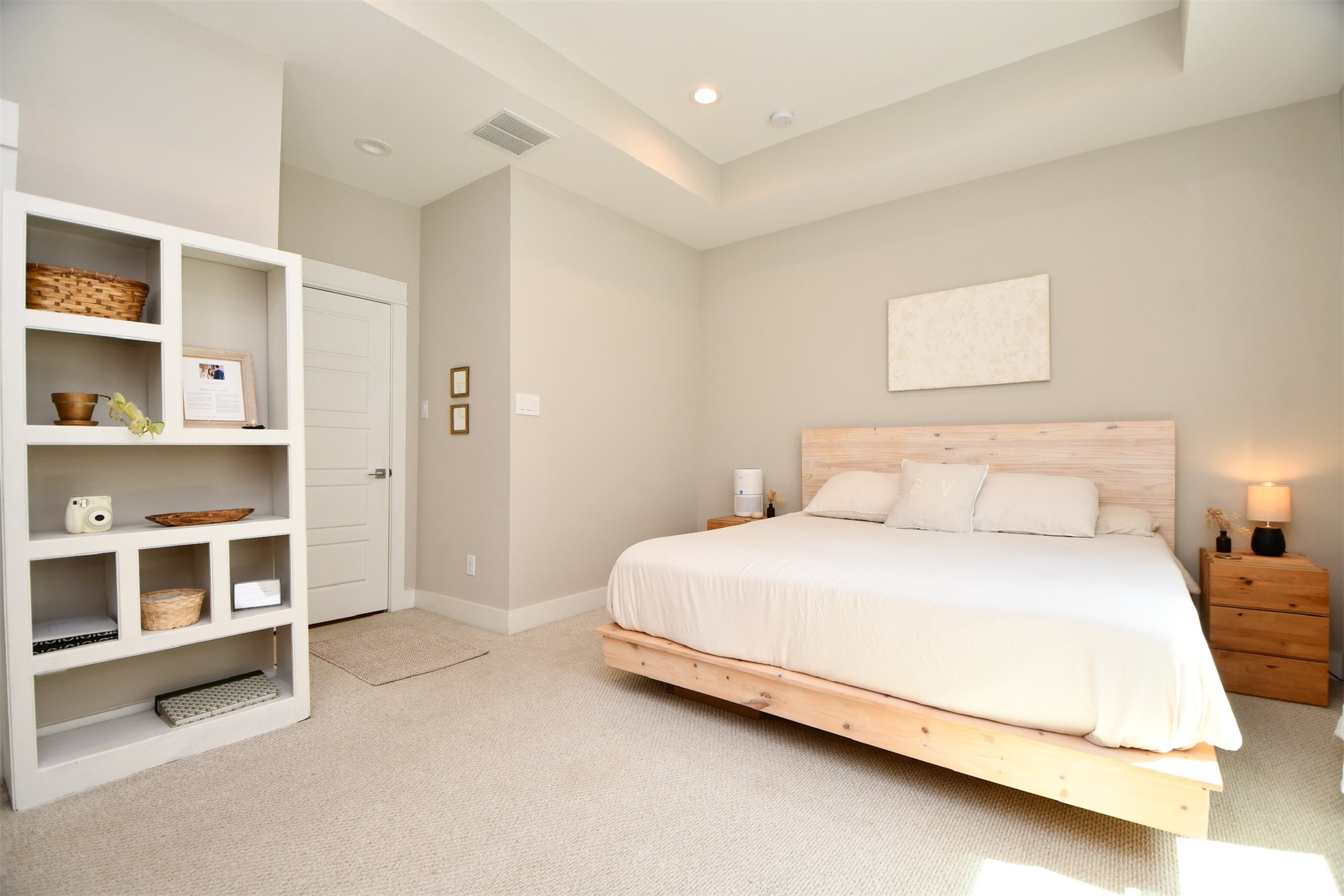1239 West Tidwell Road Houston, TX 77091 - Photo 18 of 35 This bedroom is spacious and bright, featuring a minimalist design with neutral colors. It includes a large bed with a wooden headboard, built-in shelving for storage, and soft carpeting, creating a cozy and inviting atmosphere.