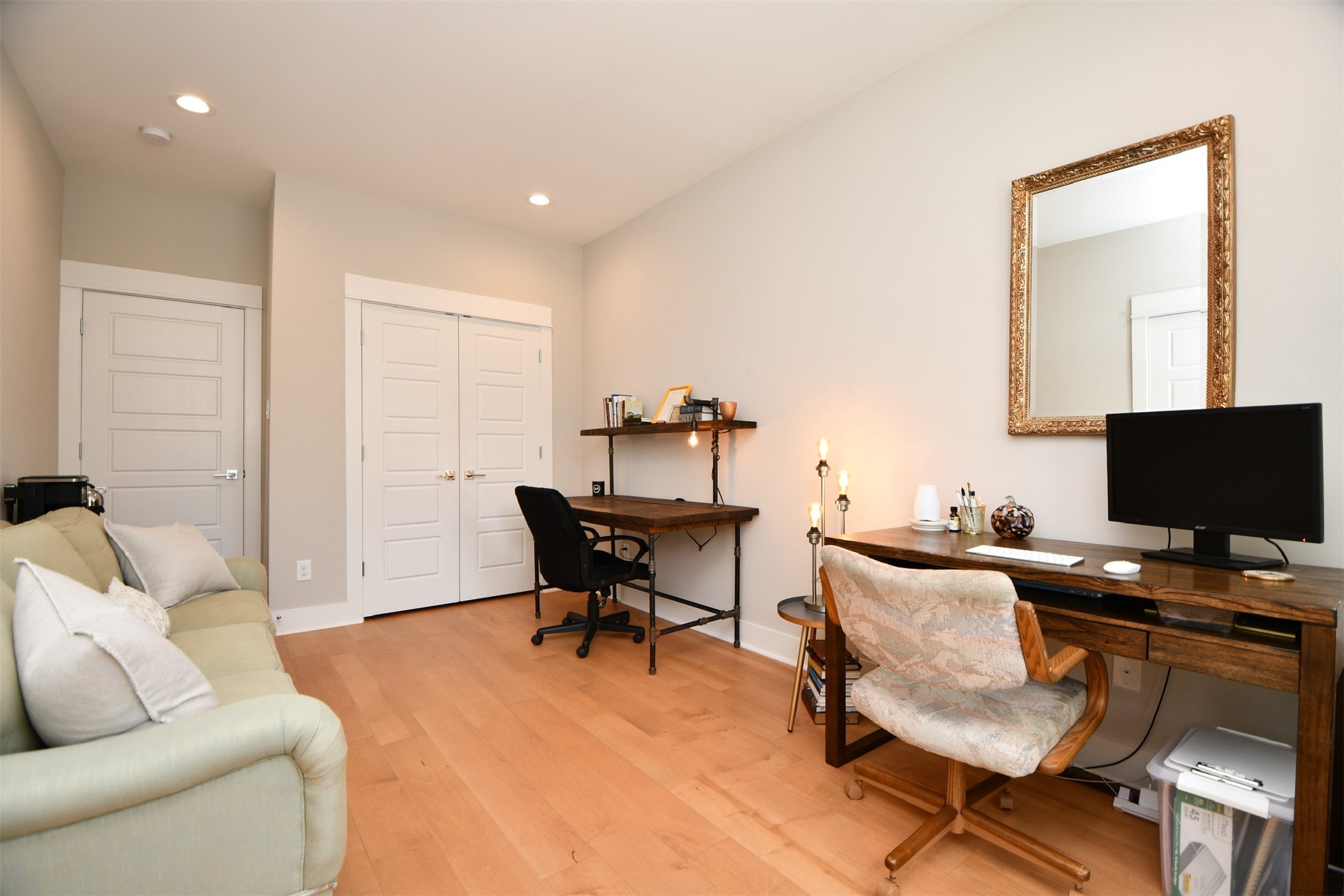 1239 West Tidwell Road Houston, TX 77091 - Photo 30 of 35 This room is a cozy home office with light wood flooring and neutral walls. It features a comfortable sofa, a wooden desk with a computer, and a decorative mirror. Recessed lighting provides ample illumination, and there's additional storage with a double-door closet.