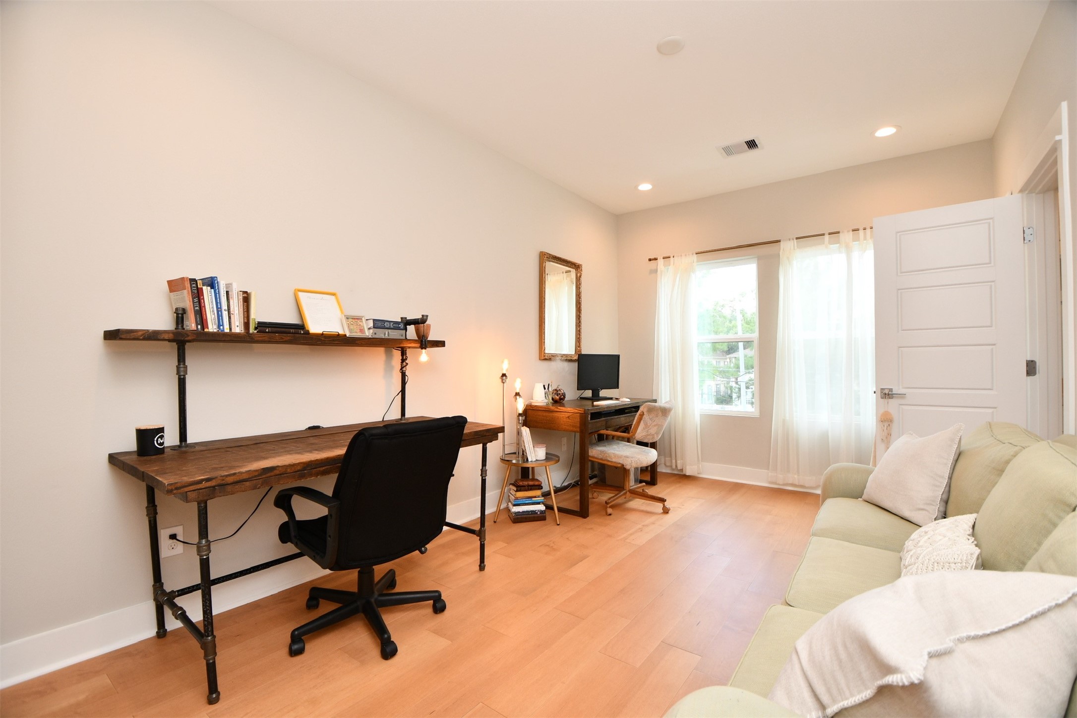 1239 West Tidwell Road Houston, TX 77091 - Photo 31 of 35 This bright home office features a cozy sofa, two workstations with wooden desks and chairs, and ample natural light from large windows. Neutral walls and wood flooring create a warm and inviting atmosphere.