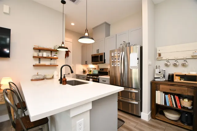 a kitchen with kitchen island a stove a sink a refrigerator and a dining table with wooden floor