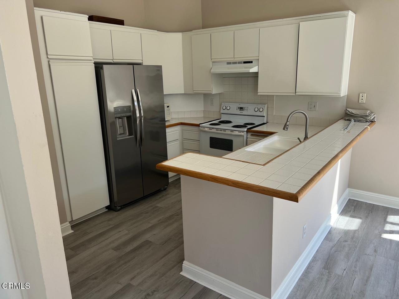 2394 Pleasant Way, Unit J Thousand Oaks, CA 91362 - Photo 5 of 12 a kitchen with a refrigerator sink and cabinets