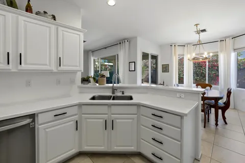 a kitchen with white cabinets and sink