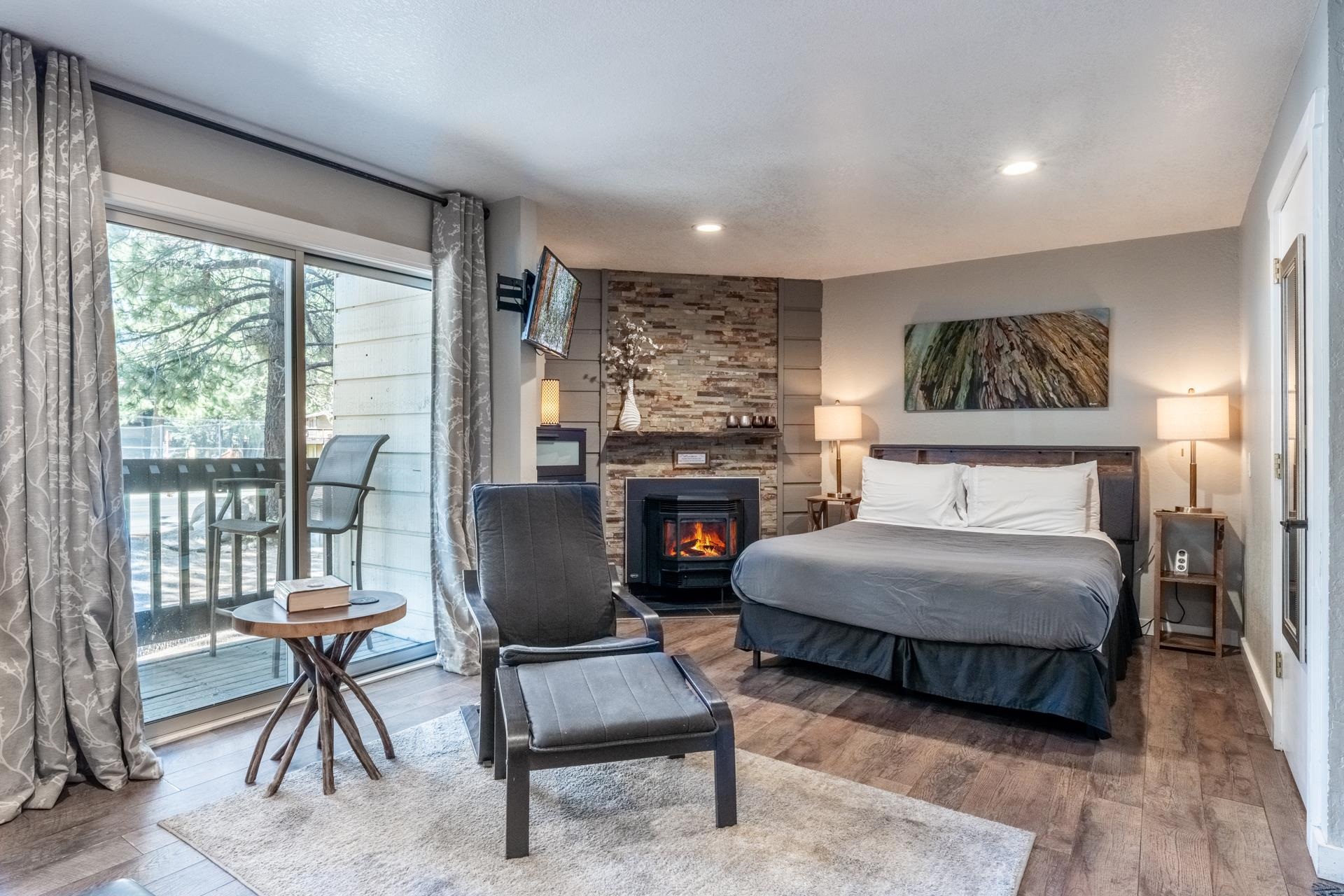 Bedroom with wood finished floors, access to exterior, a fireplace, and recessed lighting