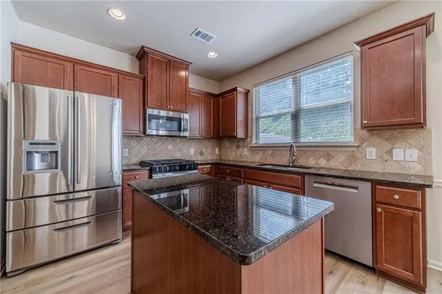 a kitchen with stainless steel appliances granite countertop a stove a sink and a refrigerator