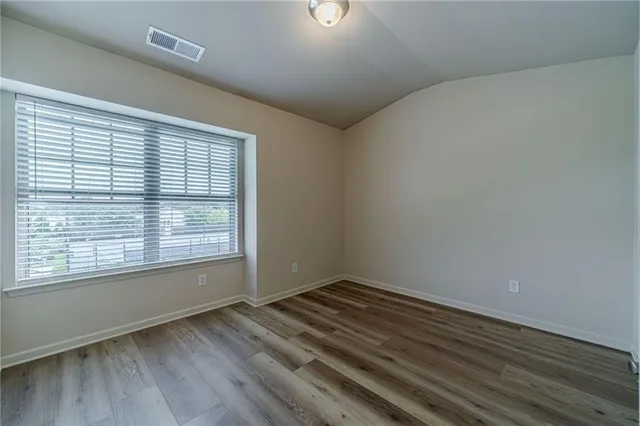 a view of empty room with wooden floor