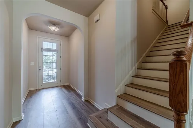 an empty room with wooden floor fireplace and windows