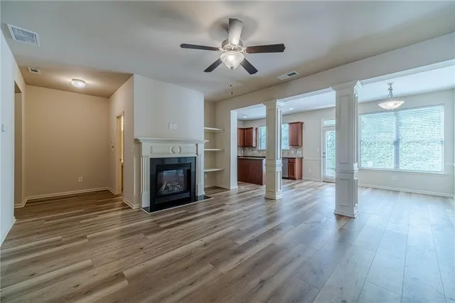 a view of an empty room with wooden floor fireplace and a window