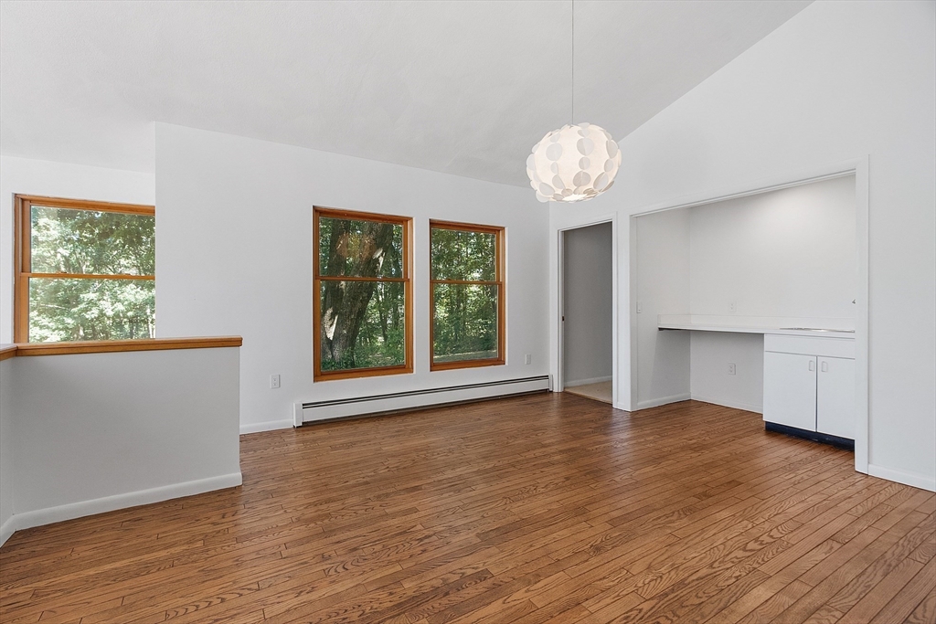 56 Old Littleton Road Harvard, MA 01451 - Photo 12 of 26 an empty room with wooden floor chandelier and windows