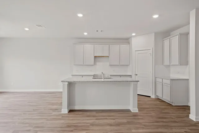 a kitchen with stainless steel appliances granite countertop a sink a stove a refrigerator and white cabinets