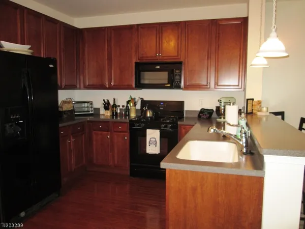 a kitchen with granite countertop wooden cabinets and black appliances