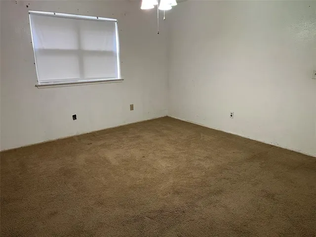 an empty room with a chandelier fan and a window