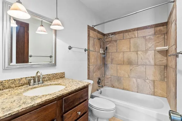 a bathroom with a granite countertop sink a toilet and shower
