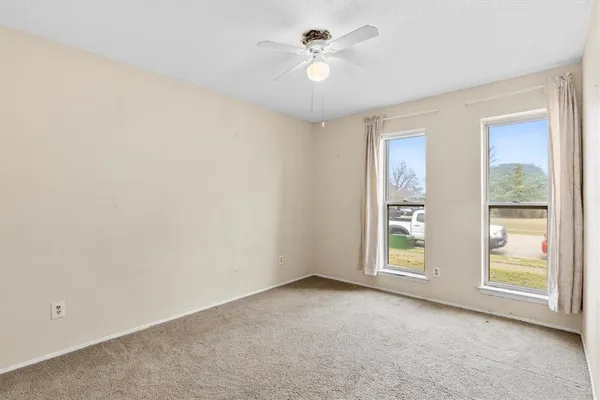an empty room with windows and fan