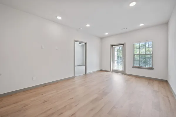 an empty room with wooden floor and windows