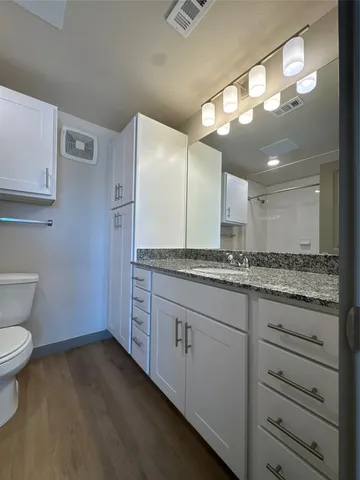 a bathroom with a granite countertop sink mirror and toilet