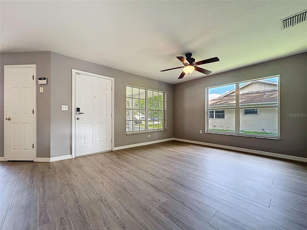 12214 Partridge Hill Row Hudson, FL 34667 - Photo 11 of 80 an empty room with wooden floor chandelier fan and windows