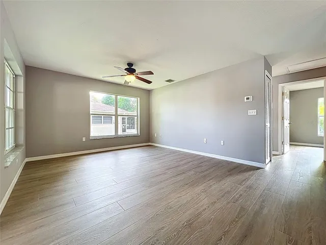 a view of a kitchen with wooden floor a refrigerator and windows