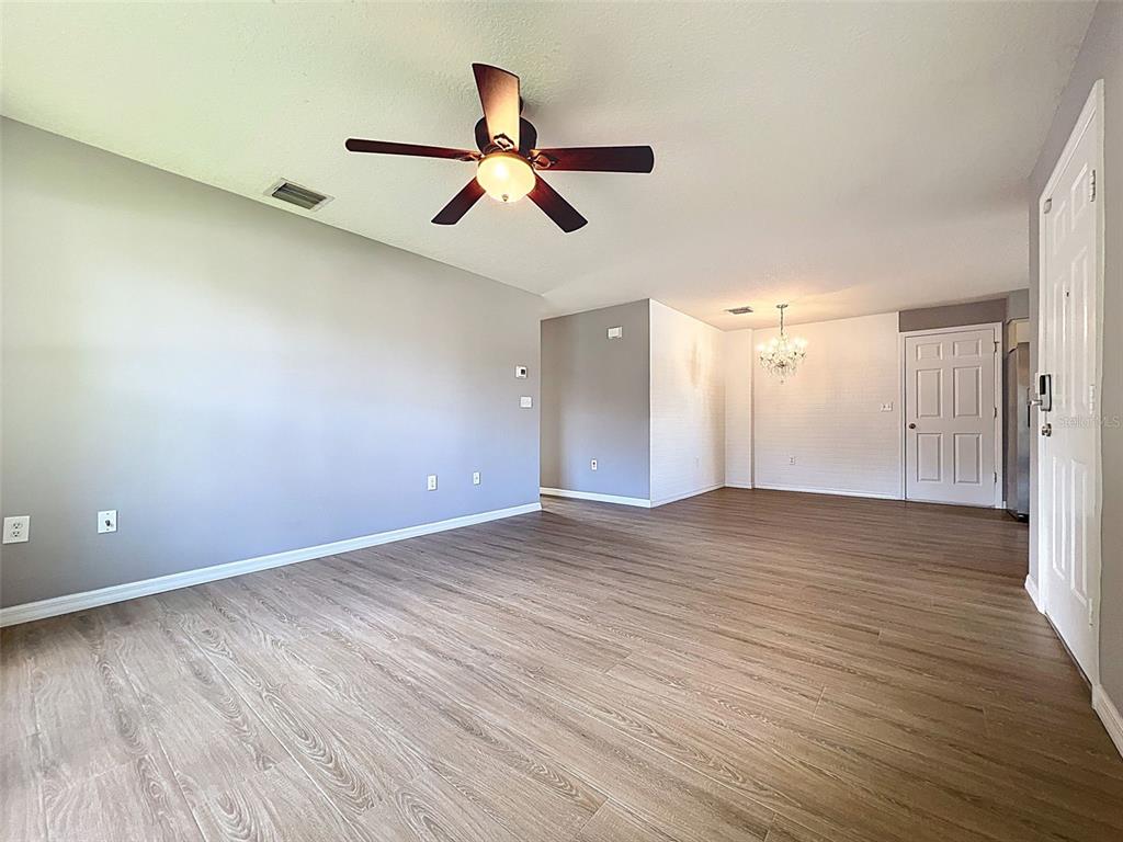 12214 Partridge Hill Row Hudson, FL 34667 - Photo 15 of 80 an empty room with wooden floor ceiling fan and windows