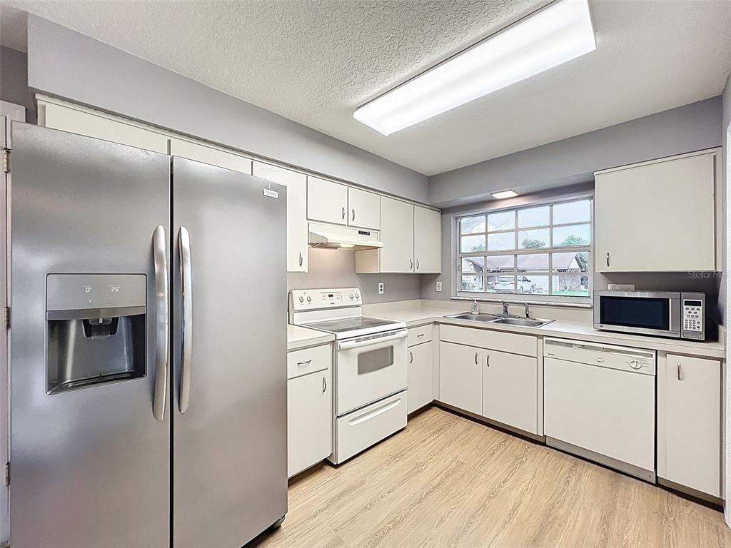 12214 Partridge Hill Row Hudson, FL 34667 - Photo 24 of 80 a kitchen with white cabinets and white appliances