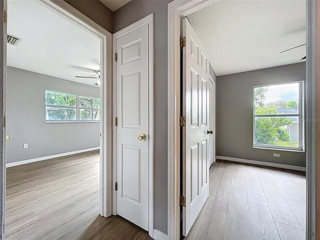 a view of an empty room with window and wooden floor
