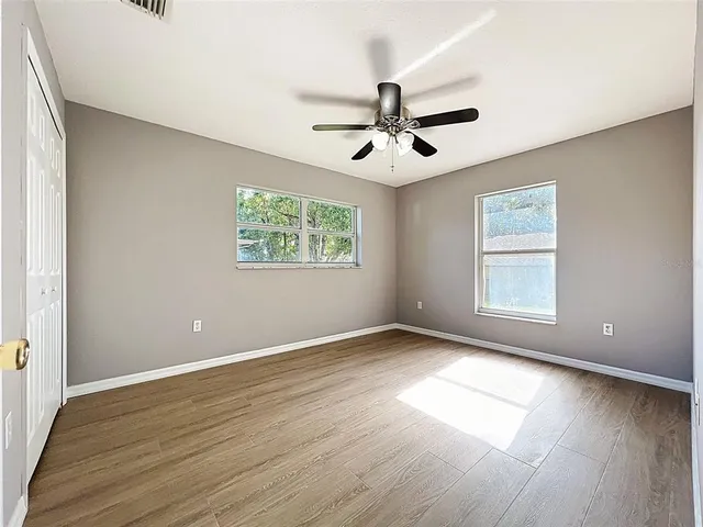an empty room with wooden floor and ceiling fan