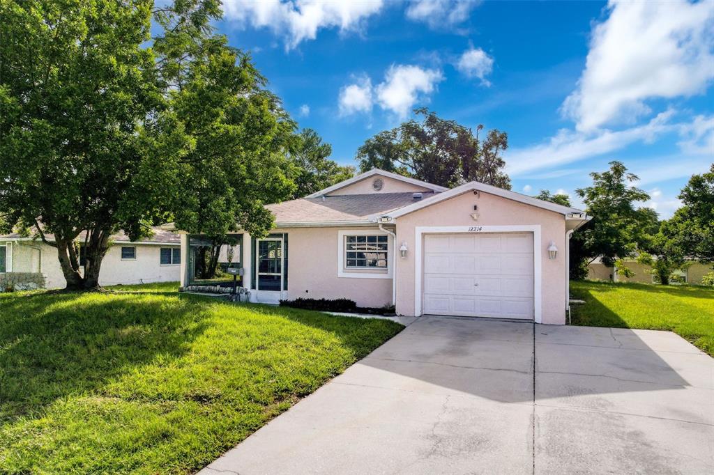12214 Partridge Hill Row Hudson, FL 34667 - Photo 4 of 80 a front view of a house with a yard and garage