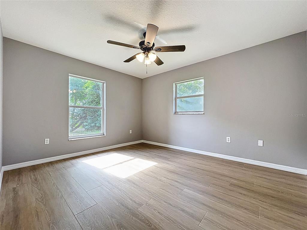 12214 Partridge Hill Row Hudson, FL 34667 - Photo 46 of 80 an empty room with wooden floor chandelier fan and windows